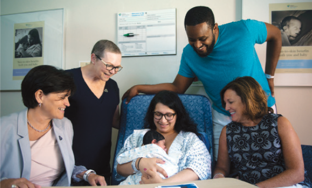 A group of health-care providers surrounding newborn and mother