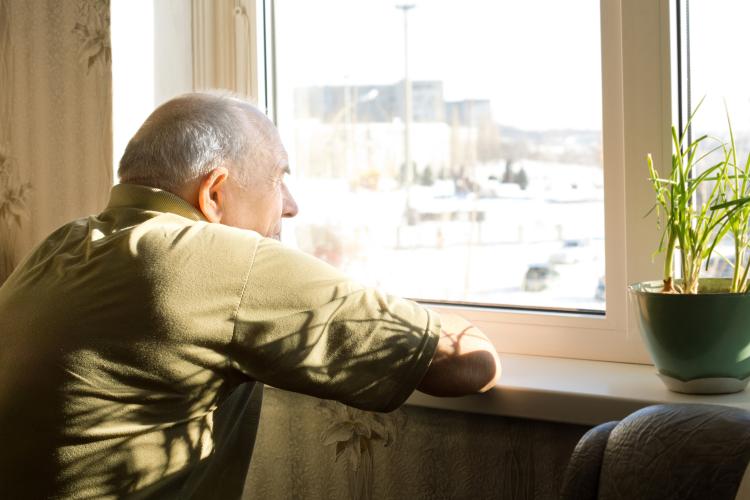 Elderly man in long-term care looks out a window