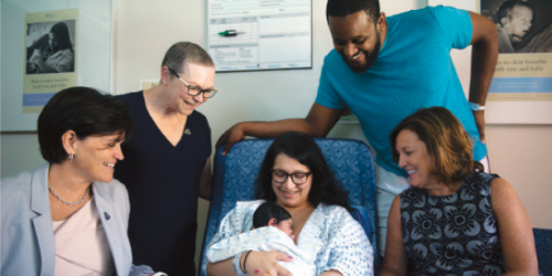 A group of health-care providers surrounding newborn and mother