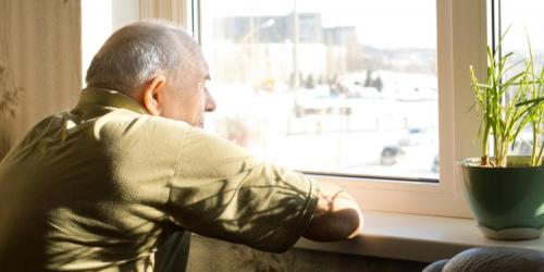 Elderly man in long-term care looks out a window