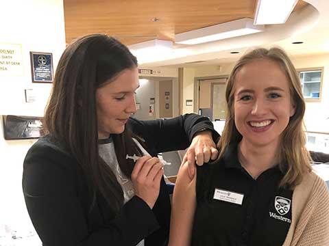 RNAO president-elect Morgan Hoffarth (left) gives the flu shot to Western student Julia Teasdale. This photo was used during  the annual flu campaign on RNAO.ca as well as the association’s social media platforms. RNAO encourages everyone to protect themselves during flu season. 