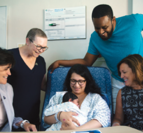 A group of health-care providers surrounding newborn and mother