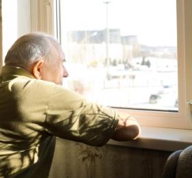 Elderly man in long-term care looks out a window